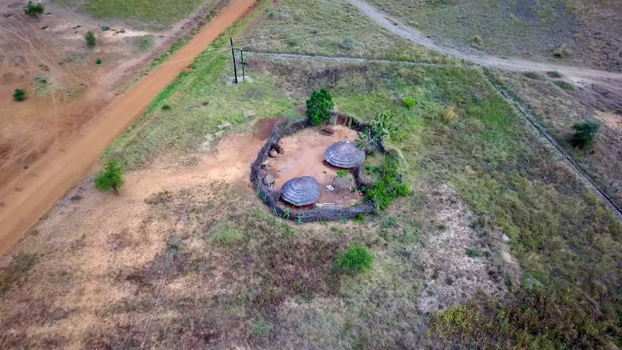 Aerial view of a small rural village in Karamoja, Uganda, showcasing traditional huts and the surrounding landscape, offering a glimpse into African rural life, drone camera tilting down