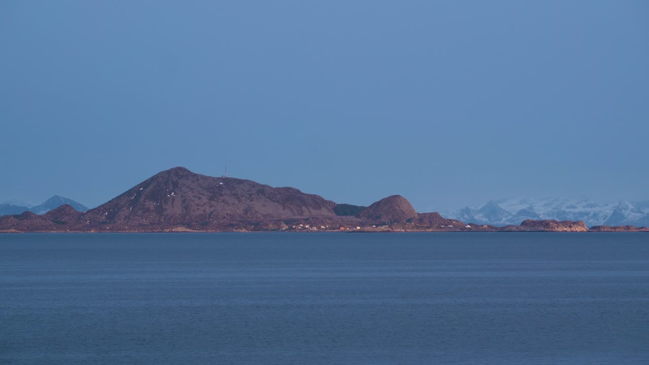 Blåt hav og himmel mødes i en bjergkæde