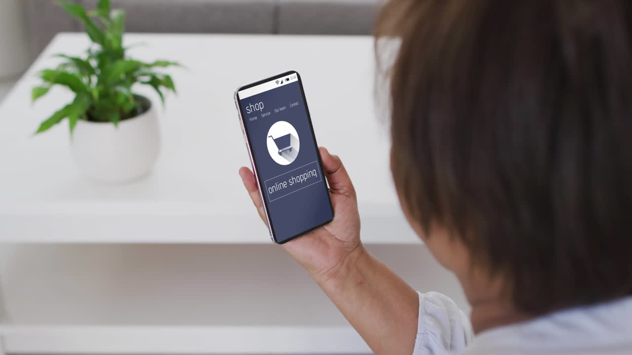 mujer biracial usando teléfono inteligente en casa para comprar en línea, cámara lenta