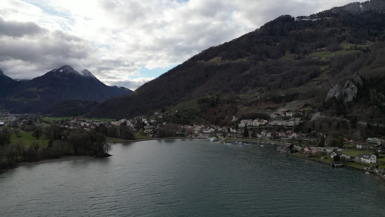 estableciendo una visión general aérea sobre la idílica ciudad en la base de los acantilados a lo largo de la costa en walensee, suiza