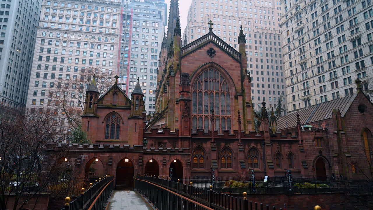 Nowy Jork, USA, 2 grudnia 2025: Fasada frontowa kościoła Trinity Church na Manhattanie z otaczającymi drapaczami chmur. Architektoniczny widok gotyckiego wejścia do kościoła i ogrodzenia na tle