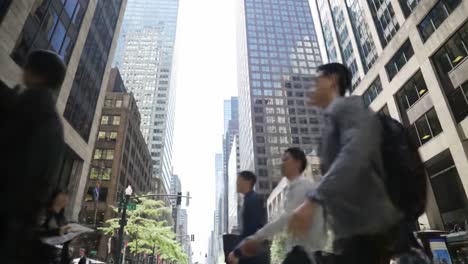 pedestrians navigate a bustling city street lined with towering skyscrapers under a bright sky, showcasing the lively urban atmosphere at midday.