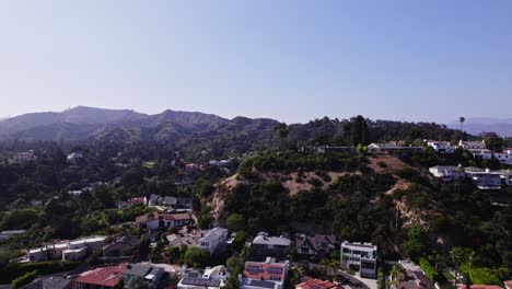 A-scenic-aerial-view-capturing-hillside-residences-surrounded-by-lush-greenery-with-mountains-in-the-backdrop,-highlighting-the-harmony-between-urban-living-and-nature