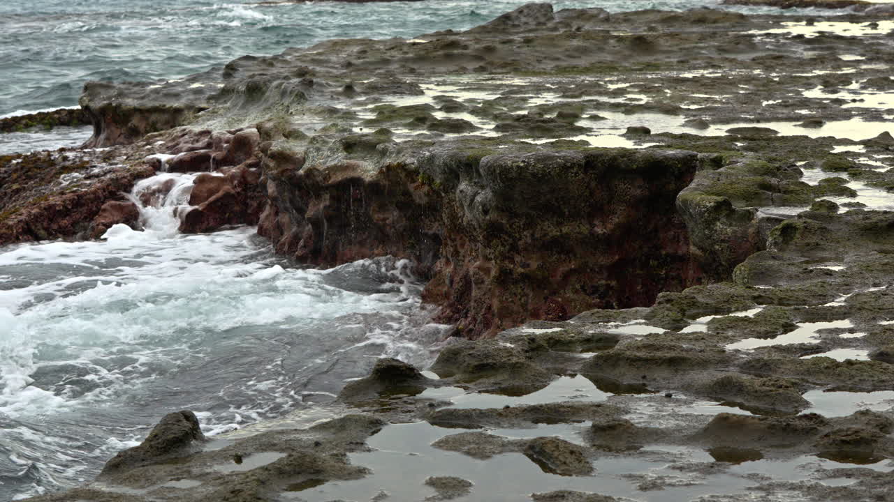 slow-motion shot of waves smashing against coral rocks at Punta Bruja