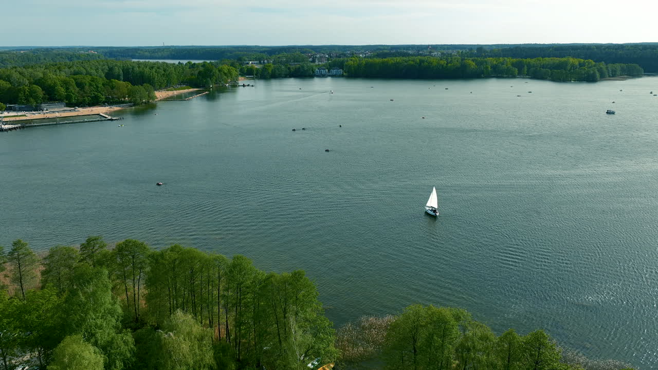 lago ukiel con un velero y varios barcos pequeños en el agua
