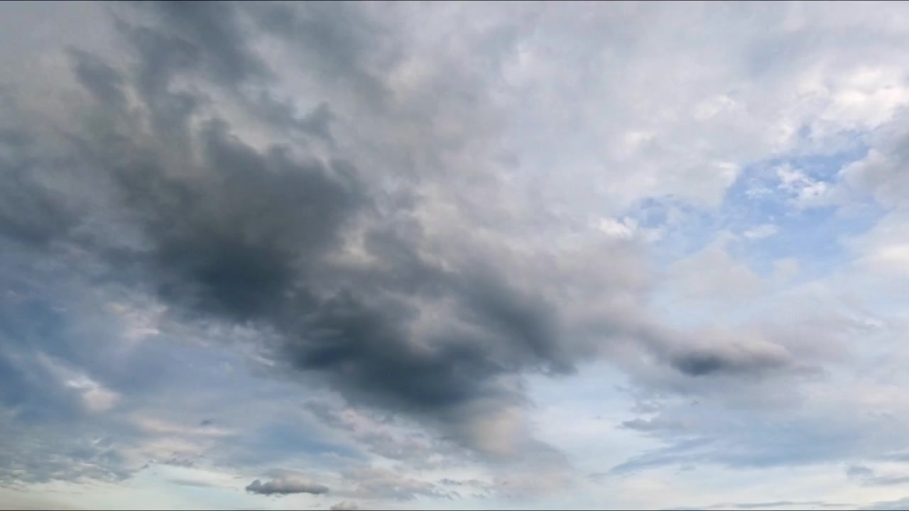Timelapse of white cumulus clouds drifting across a bright blue sky, capturing natural weather movement and peaceful atmospheric scenery.