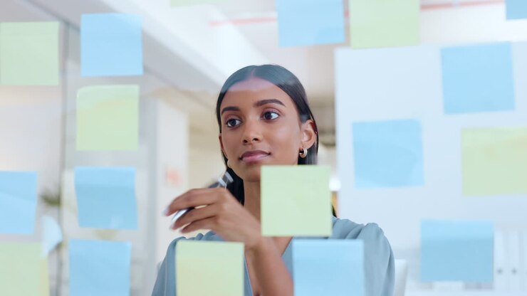 Joven mujer con notas en pared de cristal