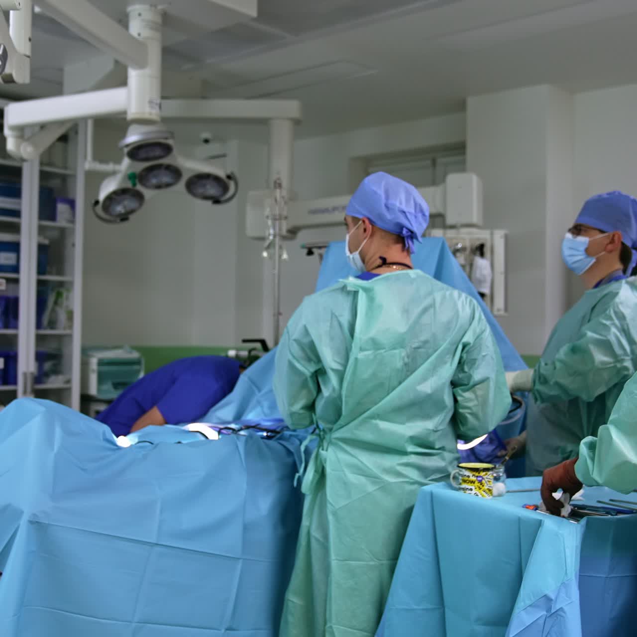 Modern well-equipped surgery room with surgery in progress. Big male medical team operating the patient looking at the monitor