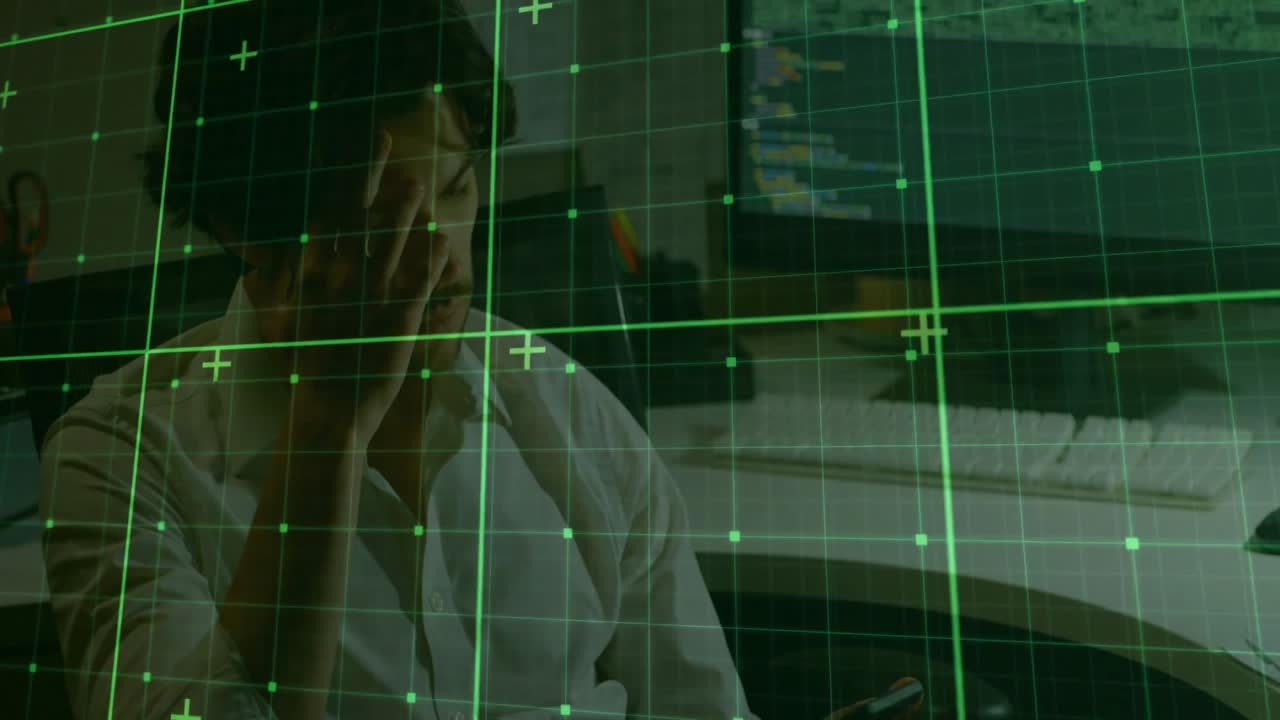 Software engineer tapping smartphone screen then glancing at monitor before typing backend code