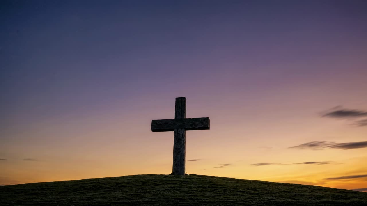 Silhouette of a cross on a hill at sunset, captured from a low-angle