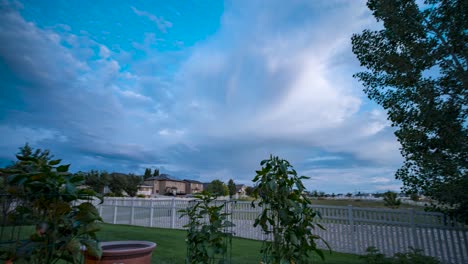 Ein-Hinterhofgarten-In-Der-Abenddämmerung-Mit-Einer-Dynamischen-Wolkenlandschaft-über-Dem-Kopf---Schwenkbewegung-Im-Zeitraffer-Nach-Oben-Kippen