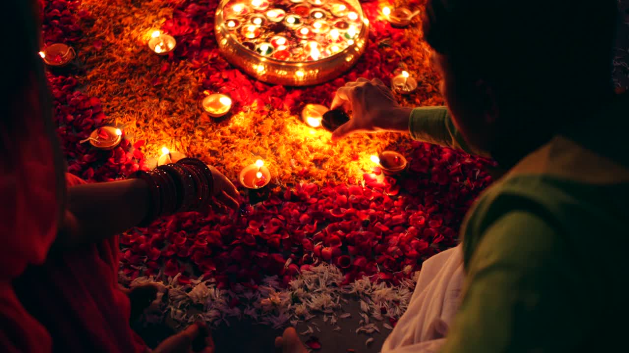 Couple celebrate a colorful Diwali rangoli- red pink orange green