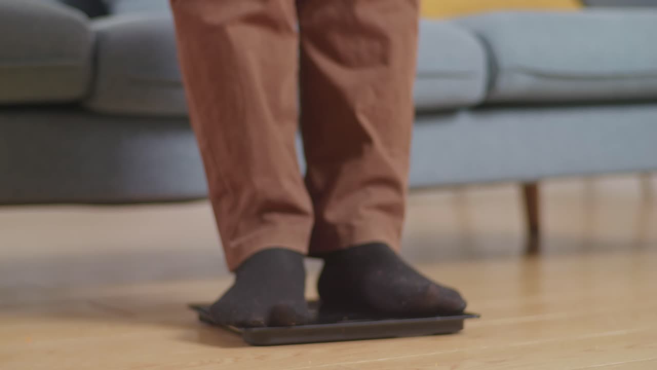 primer plano de un hombre gordo asiático pesándose mientras come comida rápida con pollo frito en la sala de estar en casa