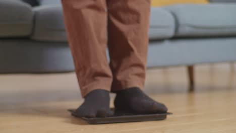 primer plano de un hombre gordo asiático pesándose mientras come comida rápida con pollo frito en la sala de estar en casa