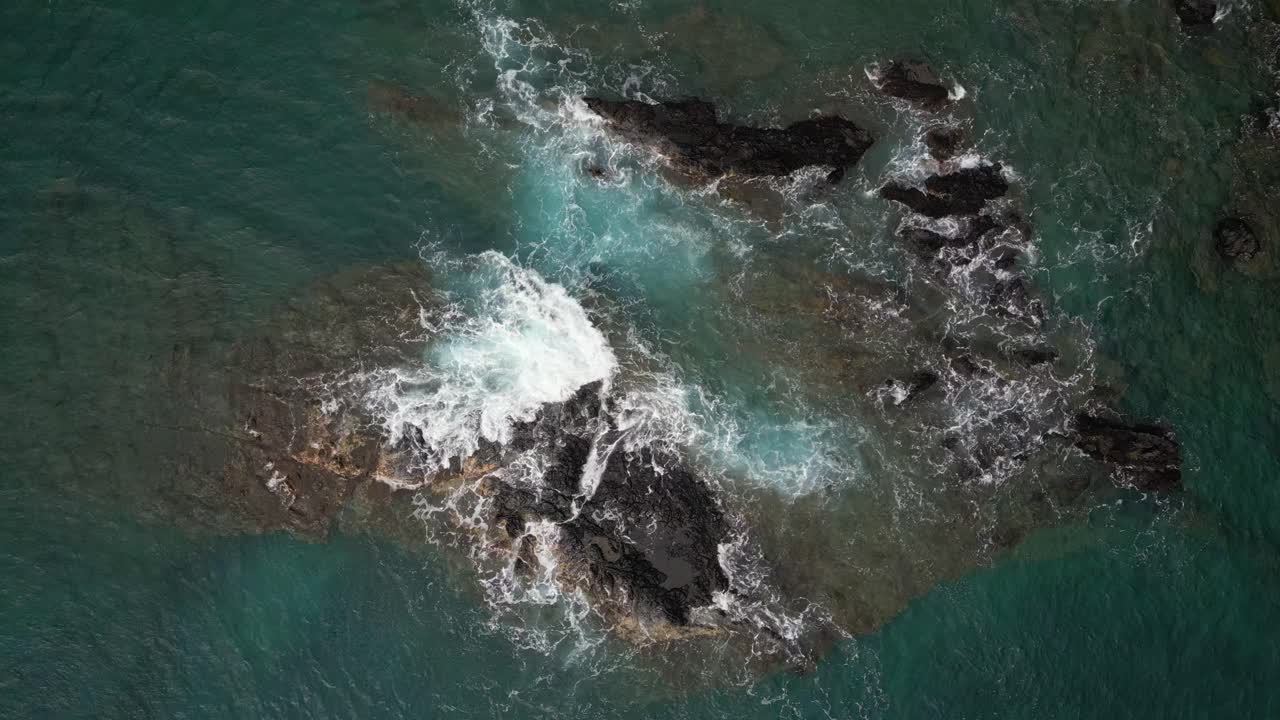 aérea de arriba hacia abajo sobre las olas rompiendo sobre las rocas