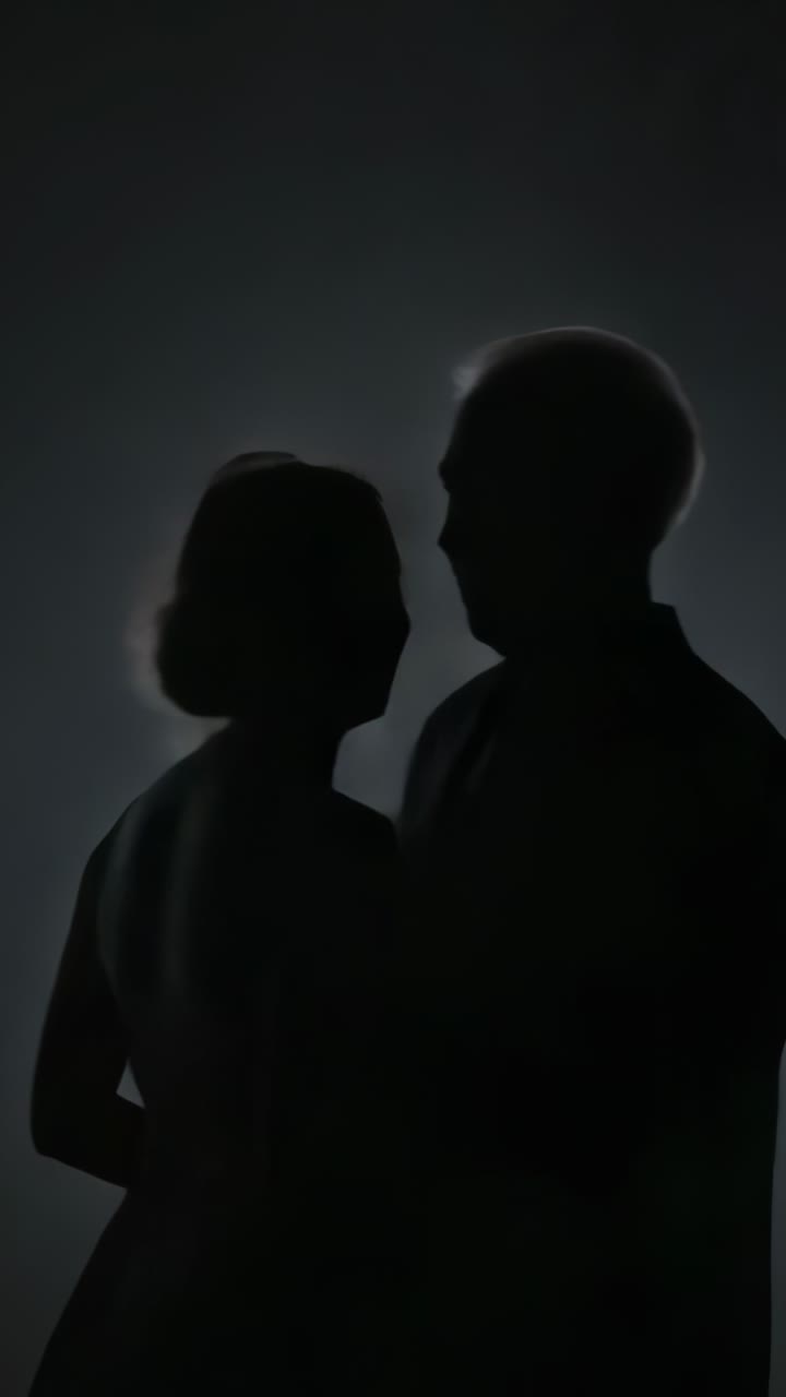 Vertical video: Turning senior couple in formal wear from closeness to handshake in backlit studio