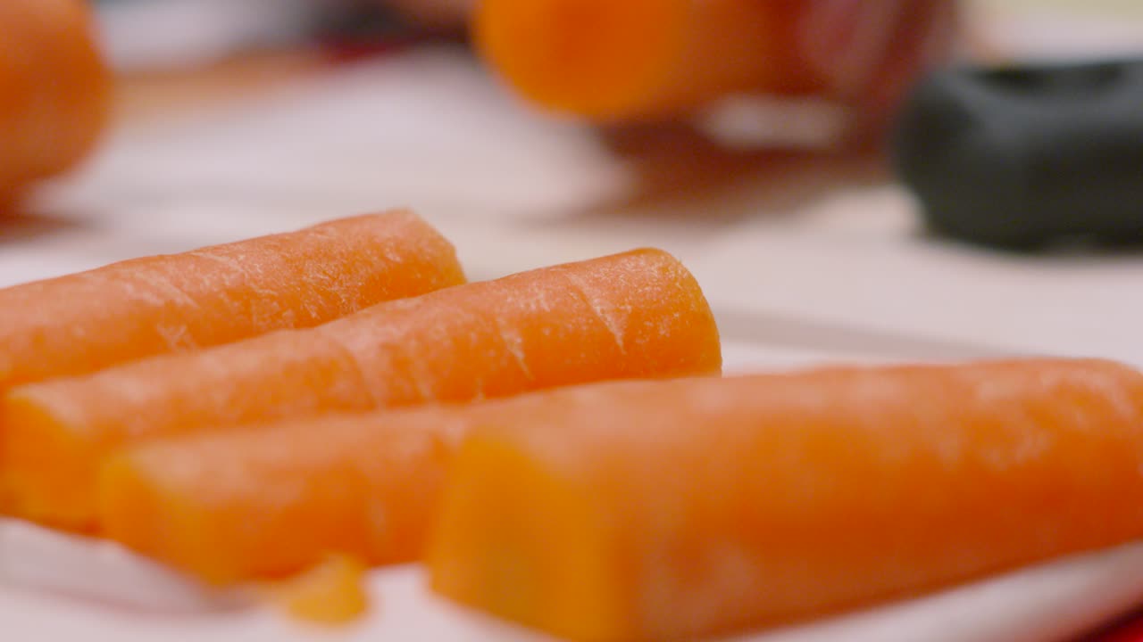 Carote fresche in preparazione, con una pronta per essere cucinata. Alimento sano, biologico e di origine vegetale. Cinematografia di alta qualità per contenuti culinari