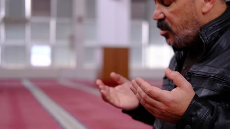 old man raising his hands and praying in the mosque