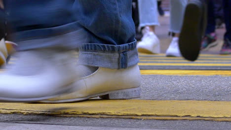 close up low angle of pedestrians crossing a crosswalk in a busy intersection in hong kong. daytime. 50fps