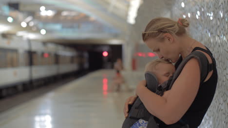 Frau-Mit-Schlafendem-Baby-An-Der-U-Bahnstation