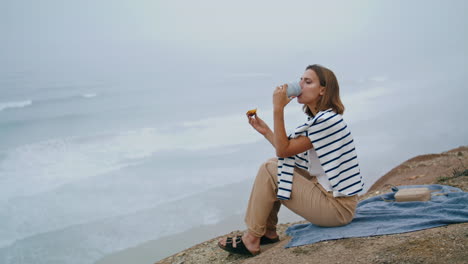niña bebe café en el acantilado el fin de semana de verano vertical. turista sereno disfruta del océano