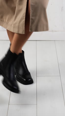 woman wearing black stylish boots jumping and dancing. square-toe leather boots presentation in studio. white backdrop. vertical video