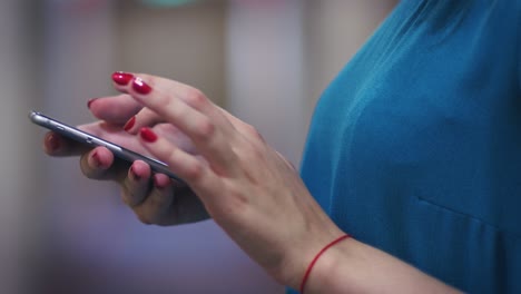 Female-hands-with-red-thread-touching-screen-on-mobile-phone-side-view