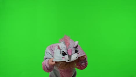 niña en pijama de unicornio haciendo caras divertidas, haciendo tonterías, mostrando la lengua en la llave de croma