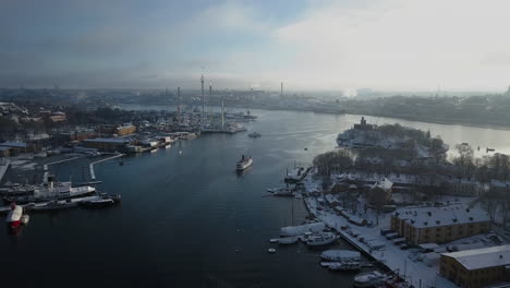 Ship-Sailing-Through-Djurgarden-Island-In-Stockholm,-Sweden-With-View-Of-Grona-Lund-Amusement-Park-On-An-Early-Morning