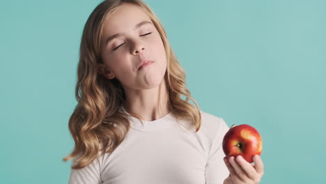 una adolescente caucásica en pijama comiendo una manzana y sonriendo.