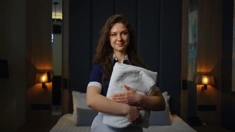 smiling hotel maid holding towel in hotel room