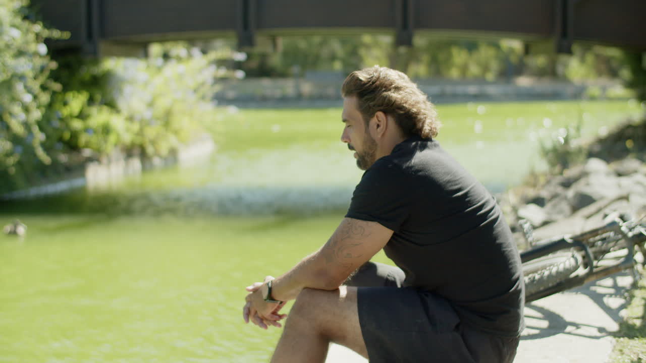 vista lateral de un hombre triste con discapacidad sentado en un banco en el parque