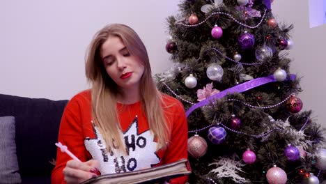 young girl in red sweater write shopping list at christmas