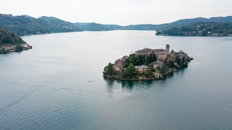 Isola-San-Giulio-En-El-Lago-Orta-En-Italia,-Aguas-Serenas-Con-Exuberante-Vegetación,-Vista-Aérea