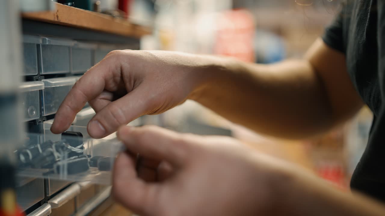 Close up of repairman's hands searching for diverse bike parts at workshop