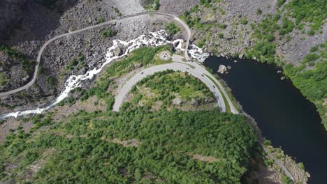 crazy good descending aerial over mabodalen mountain road leading to hardangervidda national park norway - 180 degree u turn curve from one tunnel to another - lake with river and forest surroundings