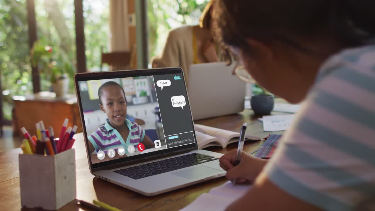 Schoolgirl using laptop for online lesson at home, with her colleague and web chat on screen