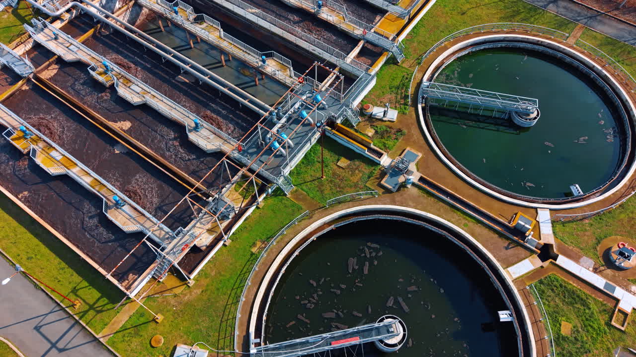 Aerial view of circular and rectangular wastewater treatment tanks. High angle shot of sewage treatment plant with sedimentation tanks and aeration basins
