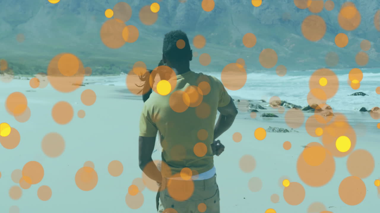 woman and man spinning on beach, promoting travel marketing with animated orange bokeh overlays