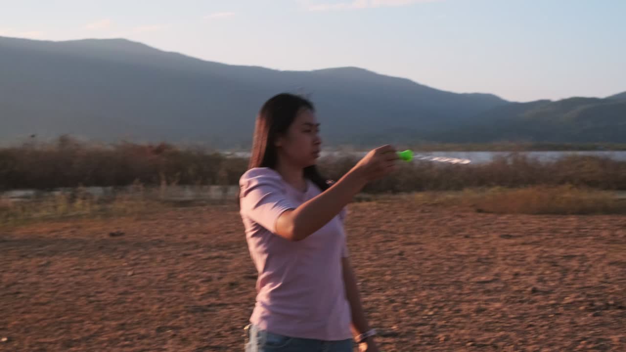 아름다운 아시아 여성이 해가 지는 여름 공원에서 비누 거품을 불어넣고 있습니다.