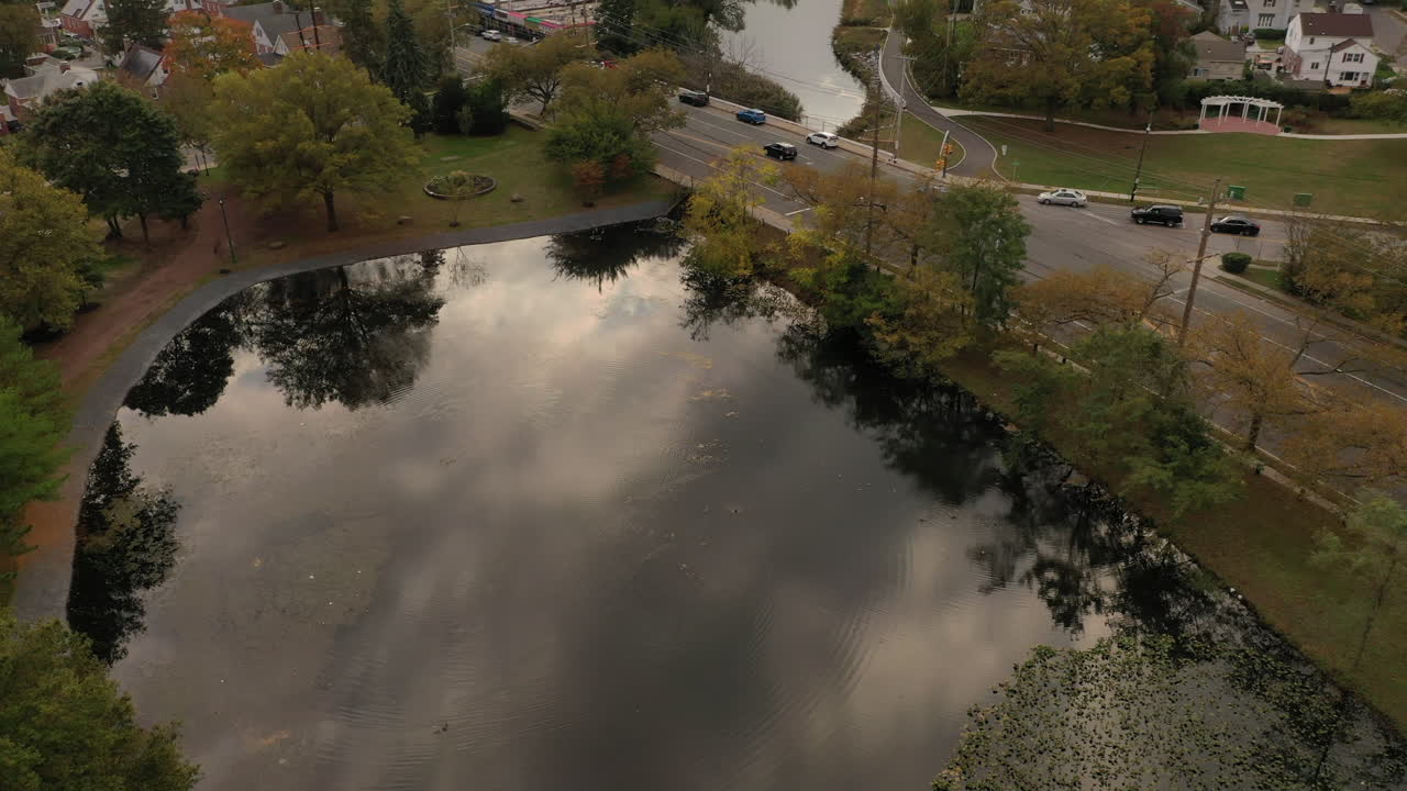 A drone shot over a reflective pond on a cloudy afternoon