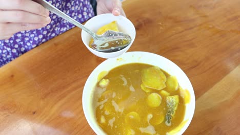 persona que sirve sopa tailandesa picante en un cuenco