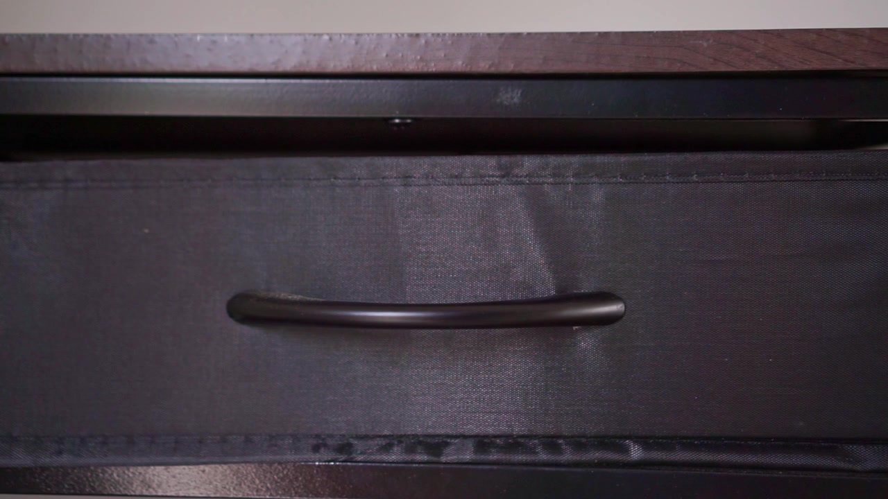 Person pulling fabric drawer handle to close storage cabinet. Home organization, decluttering, and interior design concept footage.