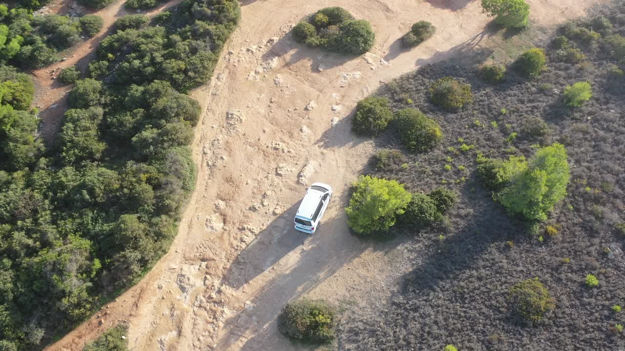 White van on dirt road approaching Fontainhas Beach in south Portugal with dogs and people walking, Aerial top view follow shot
