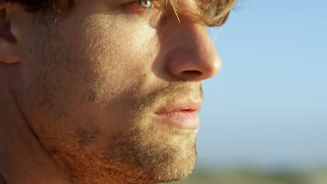 surfista masculino de pie en la playa 4k
