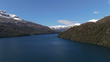 stunning aerial view of falkner lake surrounded by snow-capped andes mountain range, neuquén, argentina