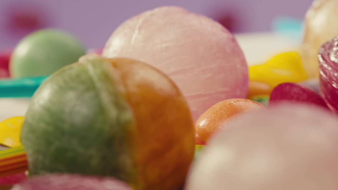Colorful dragee candies, lollipops, bonbons on white background, move in circle, side view close-up. Summer bright texture studio shot for store, supermarket. Mix of children's sweets made of sugar.