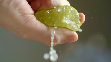 a man squeezes a lime that is cut in half while the juice squirts