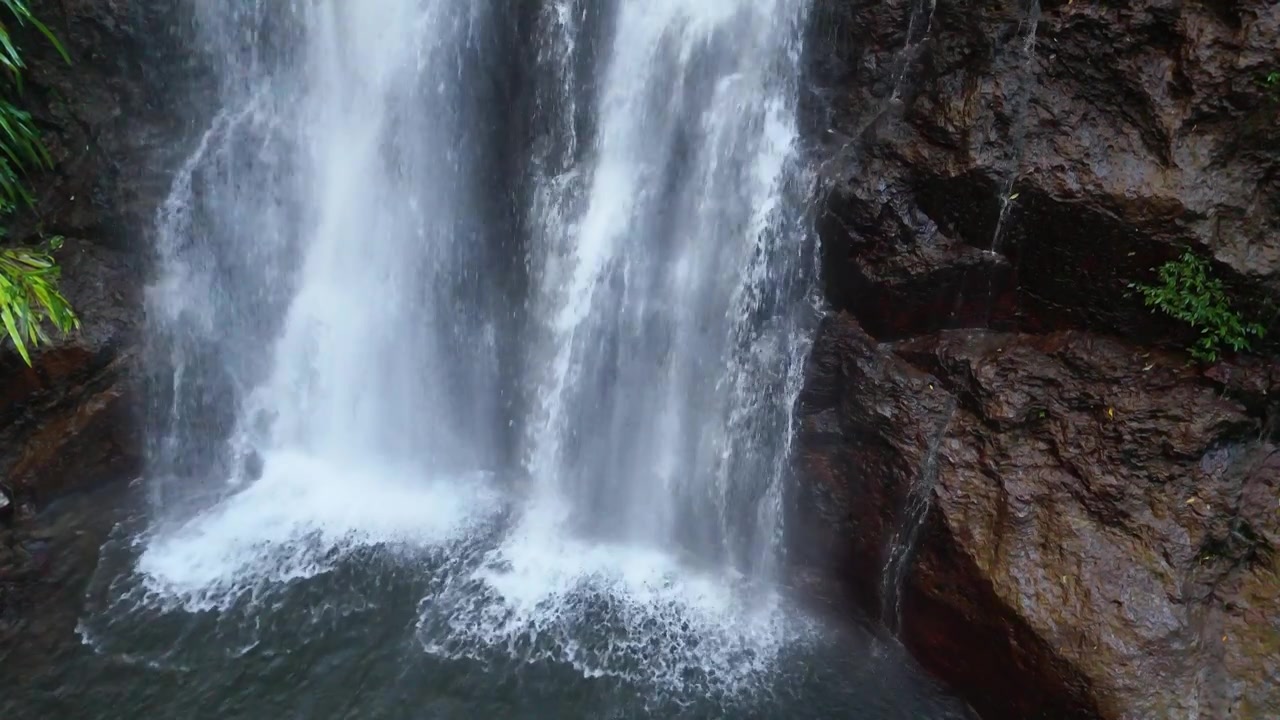 Acqua bianca cade su rocce scure e bagnate in una pozza a Binna Burra, Australia