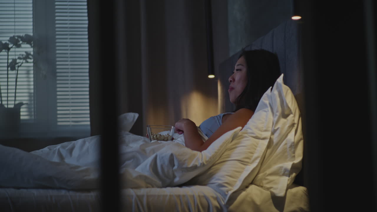 Woman eating in bed at night